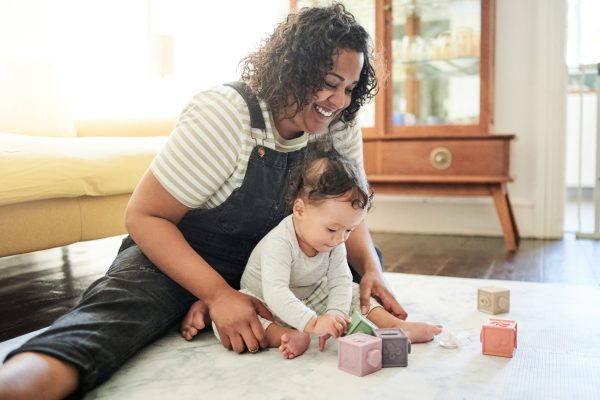 Babysitter, baby and play with blocks in home, learning and education in house. Development, care and happy nanny playing with child toys, toddler and newborn while bonding and having fun together